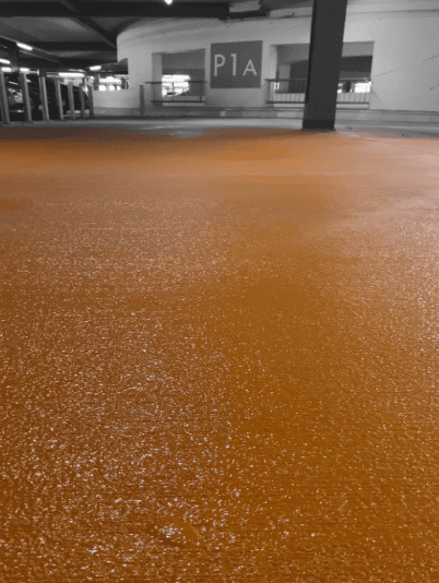 Oranger Boden im Parkhaus sorgt für auffällige, einheitliche und funktionale Optik.